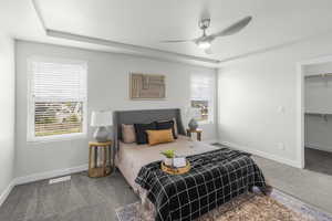 Bedroom featuring a raised ceiling, multiple windows, carpet, and visible vents
