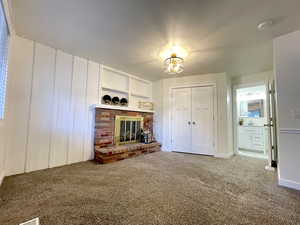 Unfurnished living room with a fireplace, carpet, baseboards, and a sink