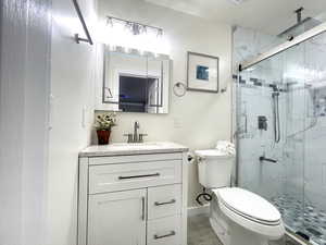 Full bathroom featuring baseboards, a shower stall, toilet, and vanity