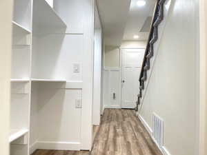 Hall with baseboards, visible vents, recessed lighting, wood finished floors, and stairway