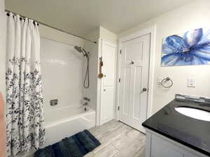 Full bathroom with wood finished floors, vanity, and shower / bath combination with curtain