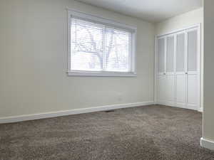 Unfurnished bedroom featuring baseboards, carpet flooring, visible vents, and a closet