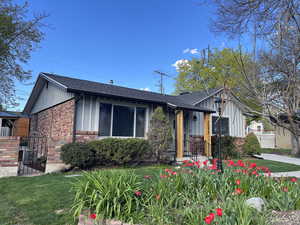 View of front of property featuring board and batten siding, a shingled roof, a front lawn, and brick siding