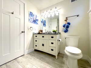 Bathroom featuring wood finished floors, vanity, toilet, and baseboards