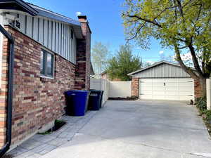 View of side of property with a chimney, driveway, board and batten siding, fence, and brick siding