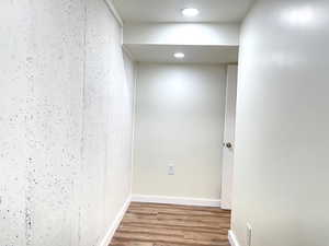 Hall featuring baseboards, wood finished floors, and recessed lighting