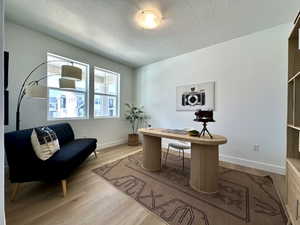 Office area featuring baseboards, wood finished floors, and a textured ceiling