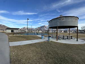 View of property's community with fence, a tennis court, a gazebo, a mountain view, and a yard