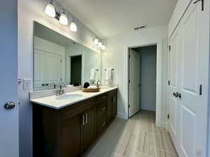 Bathroom featuring double vanity, visible vents, baseboards, and a sink