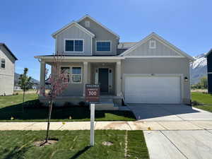 Craftsman inspired home featuring a porch, an attached garage, board and batten siding, and driveway
