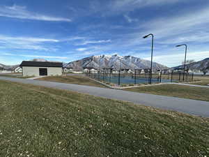Surrounding community featuring a lawn, a tennis court, fence, and a mountain view