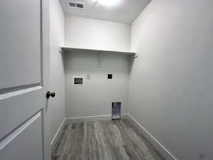 Laundry room featuring washer hookup, visible vents, baseboards, wood finished floors, and laundry area