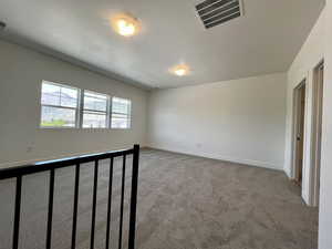 Unfurnished room featuring a textured ceiling, visible vents, carpet floors, and baseboards