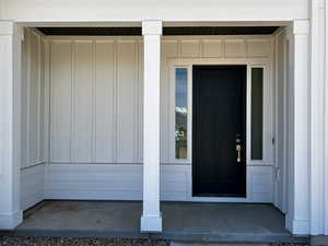 Doorway to property featuring covered porch and board and batten siding