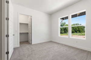 Unfurnished bedroom featuring carpet and a walk in closet