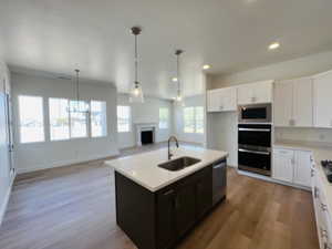 Kitchen featuring white cabinets, a sink, appliances with stainless steel finishes, light countertops, and a fireplace