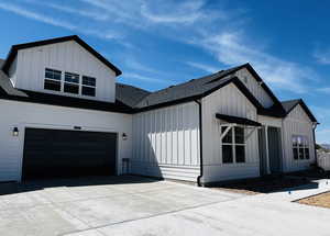 View of side of property with driveway, board and batten siding, a shingled roof, and an attached garage