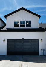 View of side of home featuring driveway, board and batten siding, and a garage