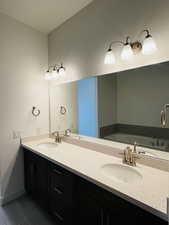 Full bathroom featuring double vanity, a sink, and baseboards