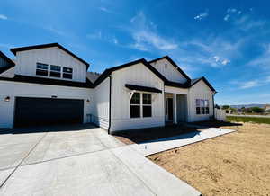 Modern farmhouse with a garage, board and batten siding, and concrete driveway