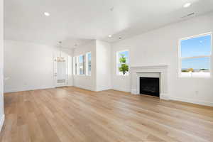 Unfurnished living room with a chandelier, light wood-style floors, recessed lighting, and a fireplace