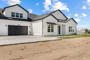 Modern inspired farmhouse featuring board and batten siding, a shingled roof, concrete driveway, and a garage