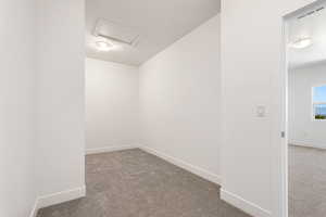 Empty room featuring carpet flooring and attic access