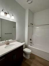 Bathroom featuring shower / washtub combination, wood finished floors, toilet, and vanity