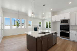 Kitchen with light wood finished floors, appliances with stainless steel finishes, a textured ceiling, white cabinets, and recessed lighting