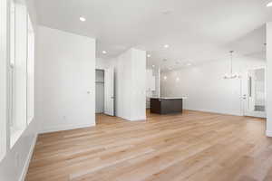 Unfurnished living room with a chandelier, light wood-style floors, and recessed lighting