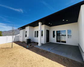 Rear view of property featuring central AC unit, a patio area, a mountain view, stucco siding, and fence
