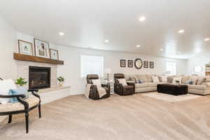 Carpeted living room featuring a healthy amount of sunlight, a tiled fireplace, recessed lighting, and baseboards