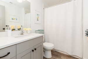 Full bath featuring visible vents, wood finished floors, toilet, and vanity