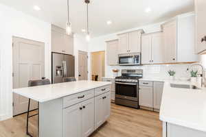 Kitchen with a sink, a center island, a breakfast bar, backsplash, and appliances with stainless steel finishes