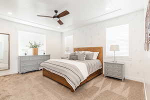 Bedroom with baseboards, light carpet, and multiple windows