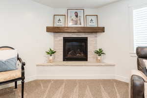Interior details featuring carpet, a glass covered fireplace, and baseboards
