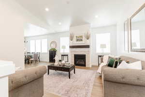 Living room featuring baseboards, a tile fireplace, recessed lighting, light wood finished floors, and vaulted ceiling