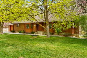 Single story home featuring a front yard, roof with shingles, and brick siding
