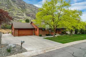 Single story home with a front yard, driveway, an attached garage, and brick siding