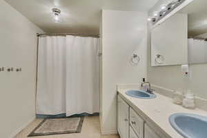 Bathroom featuring tile patterned flooring, double vanity, a sink, and baseboards