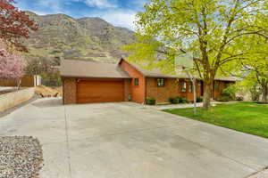 View of front of home with brick siding, fence, driveway, a front yard, and an attached garage