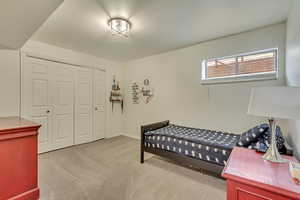 Bedroom featuring baseboards, a closet, and light colored carpet