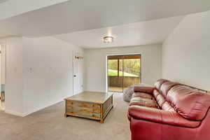 Living area featuring light colored carpet and baseboards