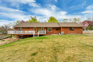 Back of house with a deck, central AC unit, and a yard