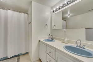 Full bath featuring double vanity, visible vents, and a sink