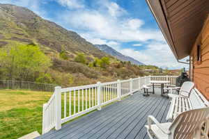 Deck with a mountain view, fence, and a yard