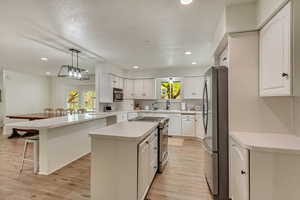 Kitchen with stainless steel appliances, light wood-style floors, a kitchen breakfast bar, and plenty of natural light