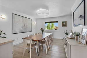 Dining space featuring crown molding, light wood-style flooring, and baseboards