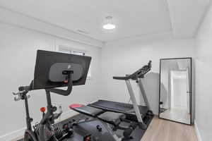 Exercise area featuring visible vents, baseboards, and light wood-style floors