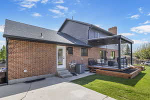 Rear view of house featuring a chimney, a shingled roof, central air condition unit, a yard, and brick siding